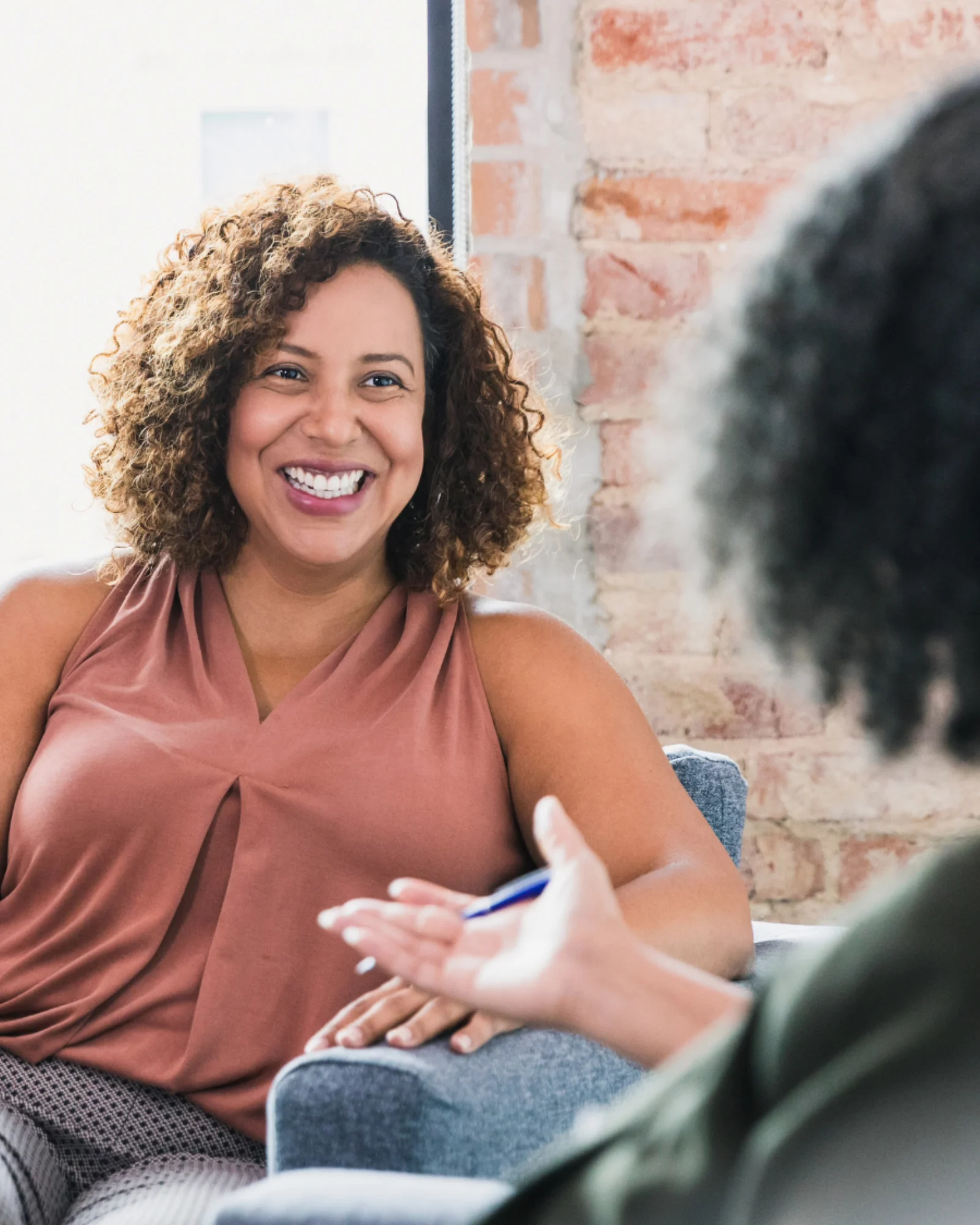 A psychologist and an adult client smiling in conversation during a session