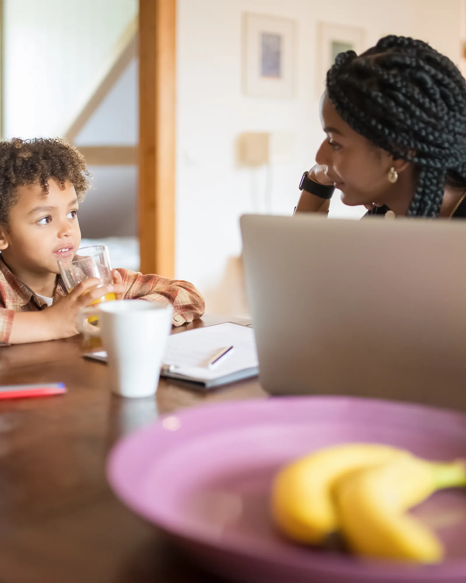 A mother and her young son sit at the kitchen table talking over breakfast.